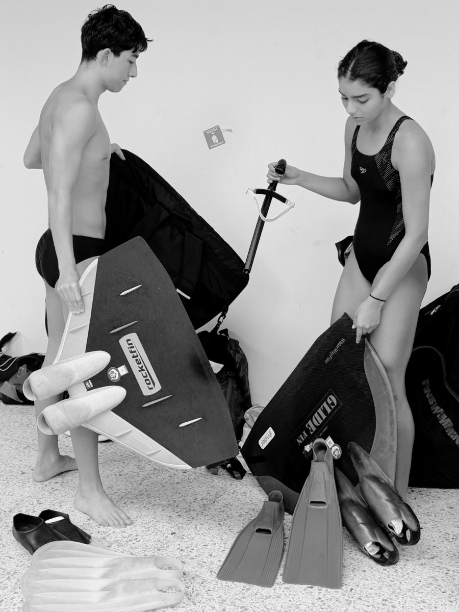 Two athletes packing away monofins and gear after training