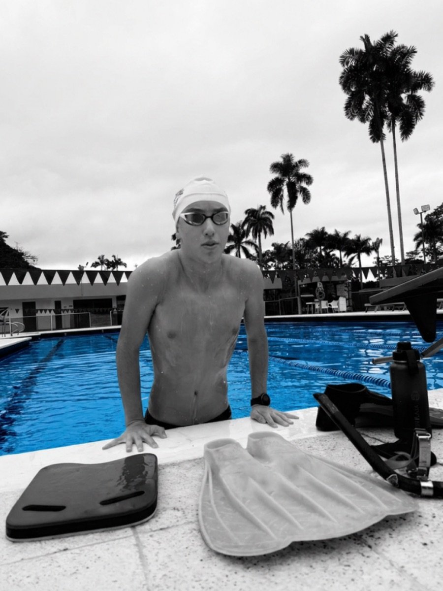 Konsta leaning on the pool edge next to his board and monofin